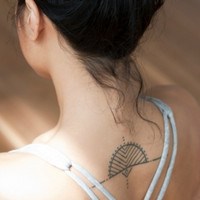 A fair skin brunette showing her upper back tattoo that one of the TKTX Tattoo Numbing Cream